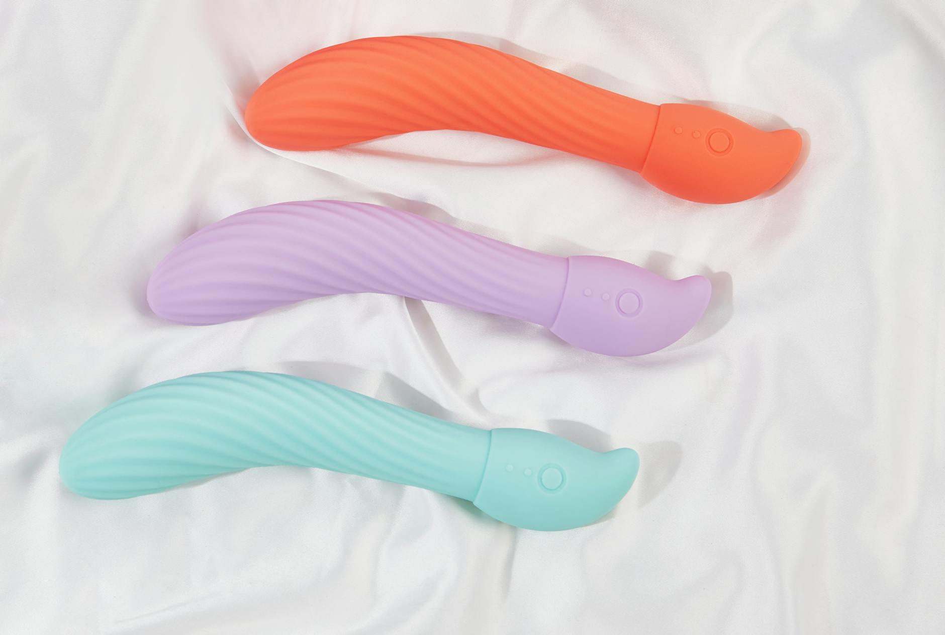 Colorful silicone vibrators displayed on a bright yellow background, showcasing modern pleasure tools