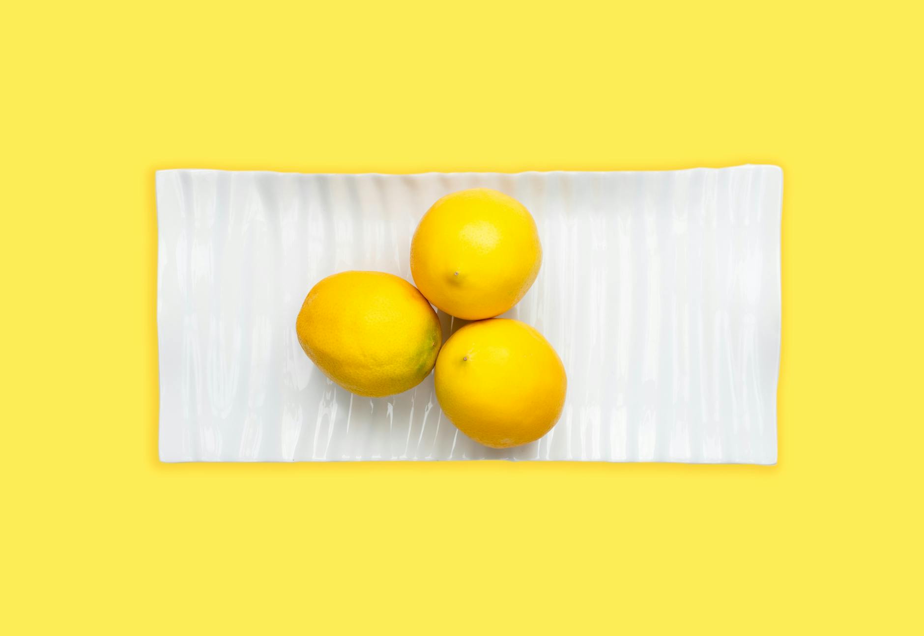 A blue vibrator surrounded by flowers and citrus on a bright yellow background