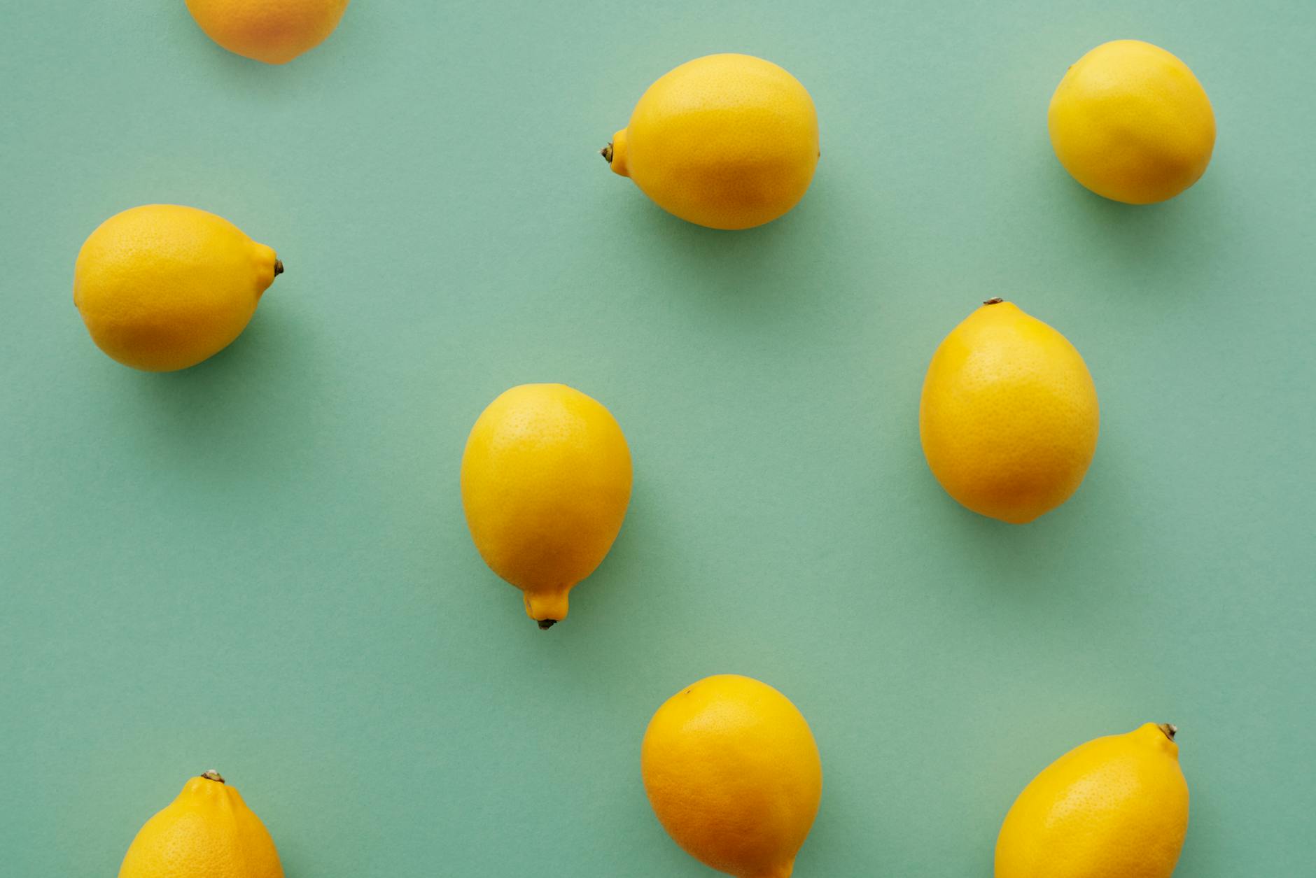 Hand holding a lemon against a soft pink background surrounded by additional lemons, symbolizing daily variation and sensitivity shifts.