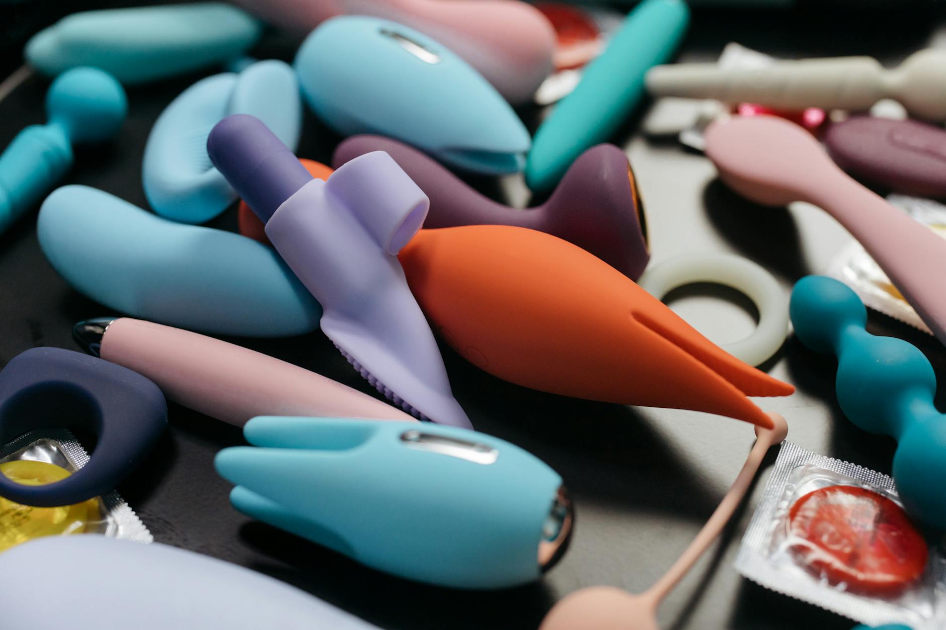 Hand holding a vibrant personal massager against a minimalist backdrop