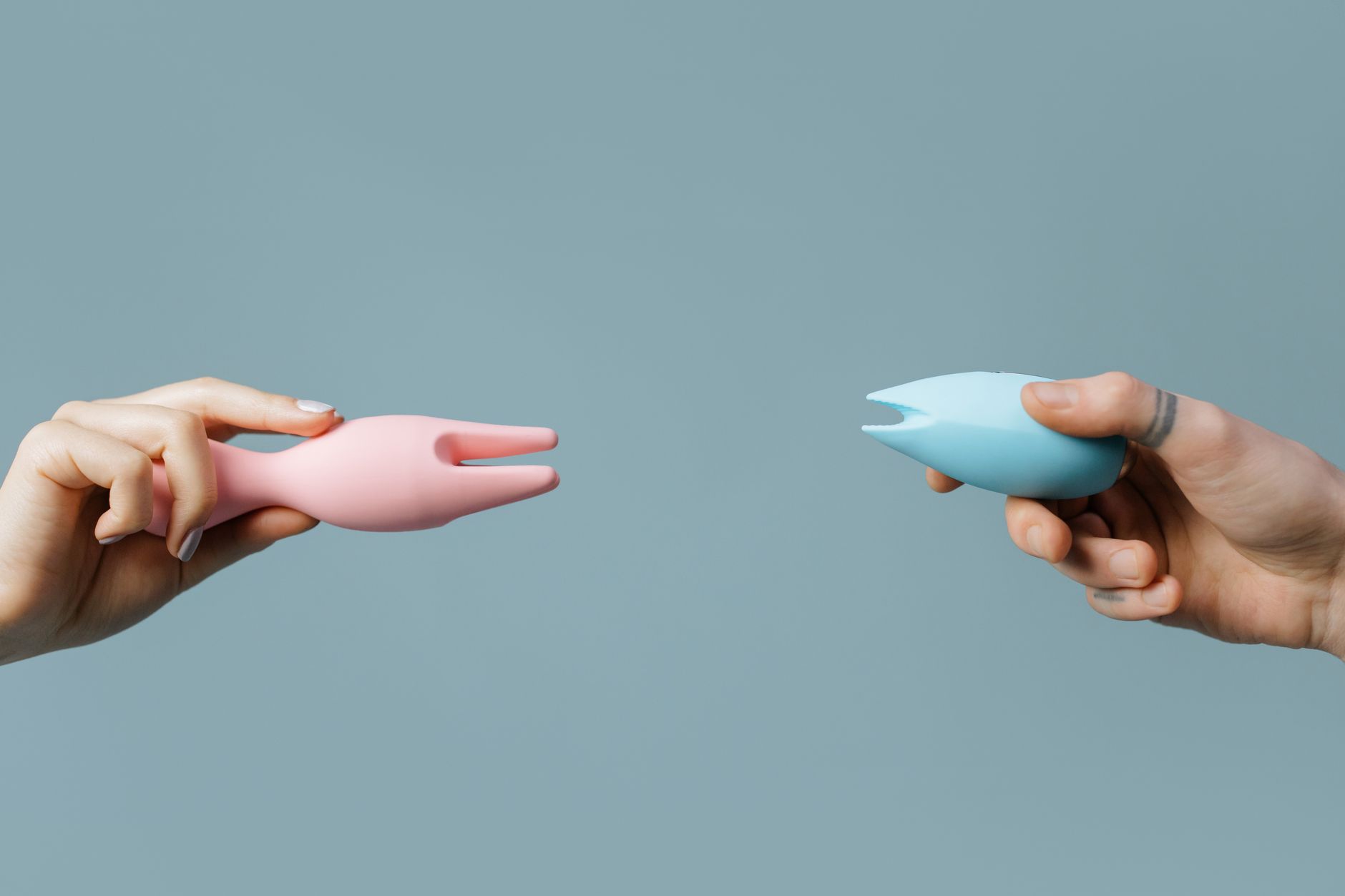 Close-up of hands holding a blue personal massager against a knitted sweater