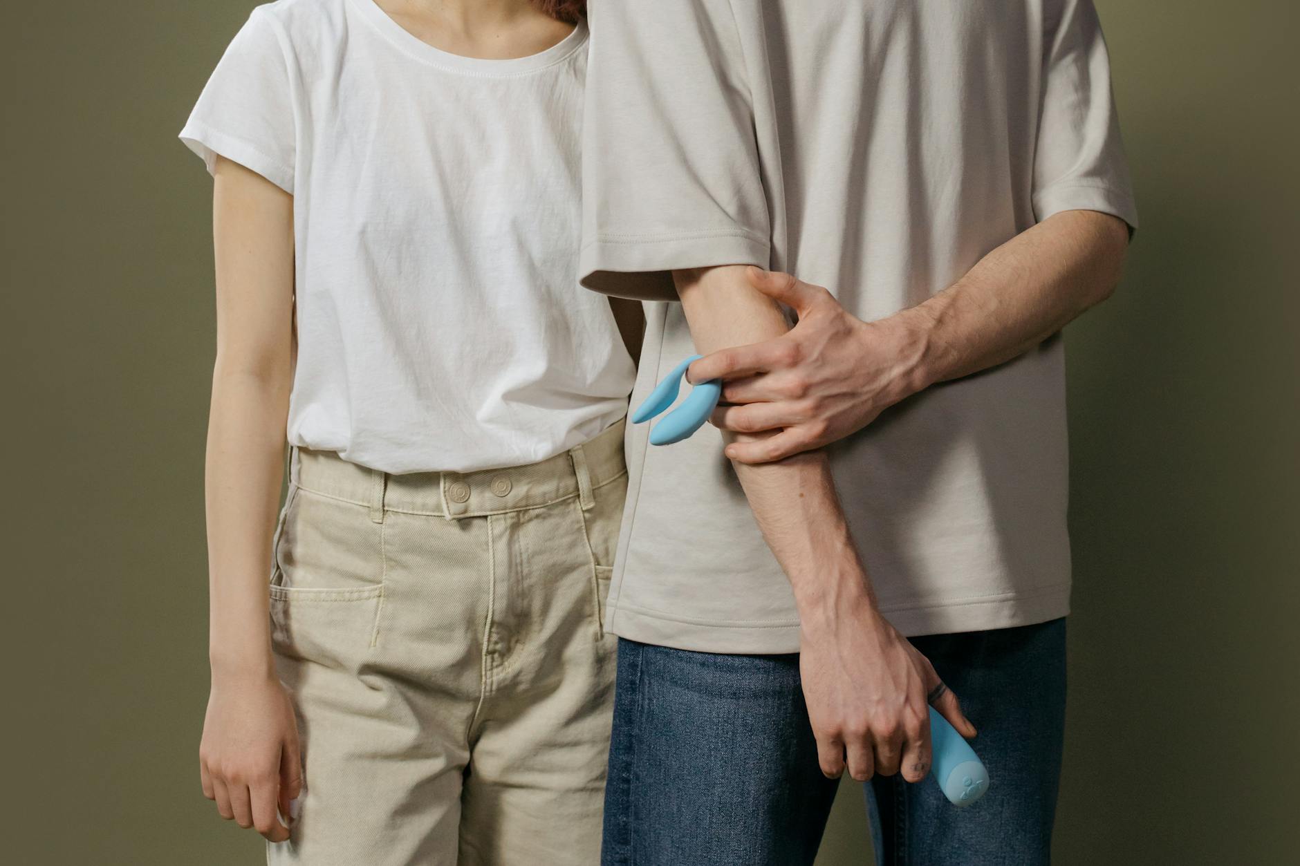 Close-up of a hand holding a blue silicone vibrator against a purple background, symbolizing personal pleasure and self-discovery in intimate relationships.