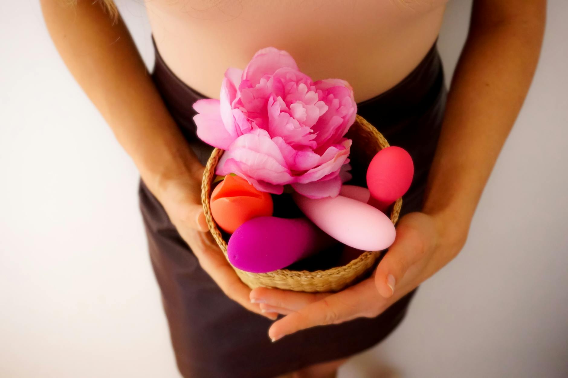 Hand with white nails holding a lemon on pink background, symbolizing the gentle approach lemon vibrators take with sensitive tissue